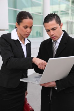 A team of business professionals looking at a laptop clipart