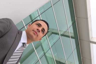 Young executive standing outside a modern office building clipart