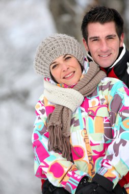 Couple huddling together on a winter's day clipart