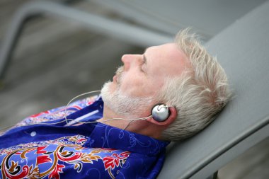 Man laying on deck chair listening to music clipart