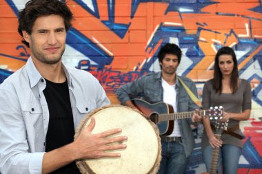 Three musicians in front of a tagged wall clipart