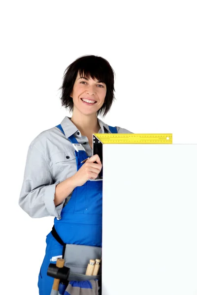 Carpinteiro fêmea com uma tábua deixada em branco para sua cópia — Fotografia de Stock