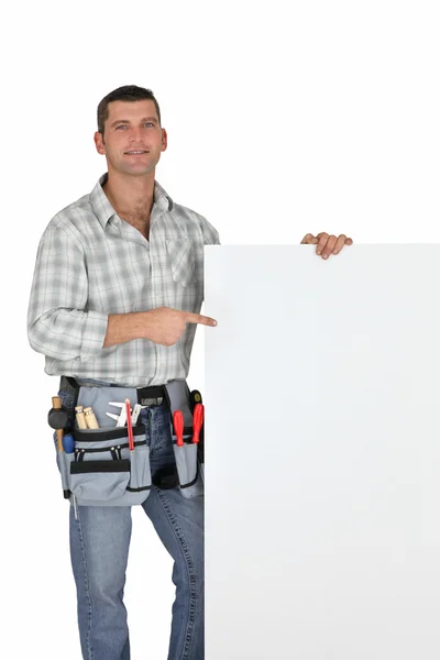 Handwerker zeigt auf leeres Plakat — Stockfoto