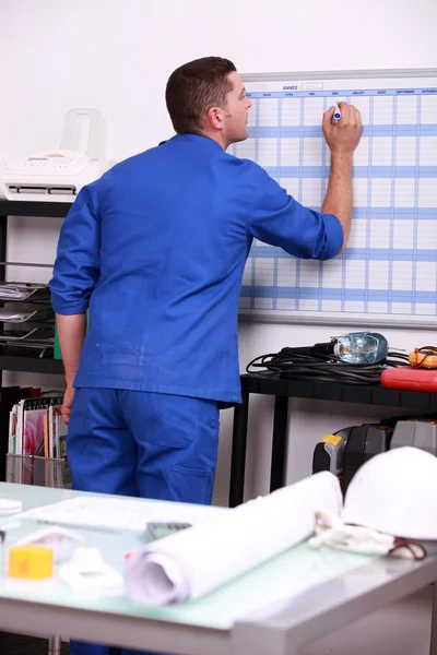 Young technician writing on a calendar — Stock Photo, Image