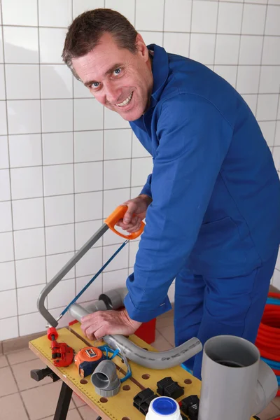 Sorrindo encanador serrar tubo de plástico — Fotografia de Stock