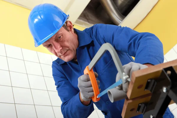 Plumber sawing a pipe — Stock Photo, Image