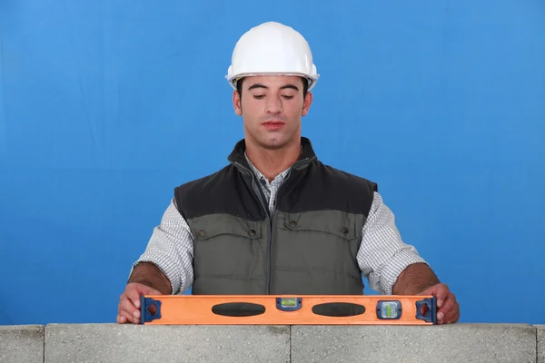 Bricklayer with a spirit level — Stockfoto
