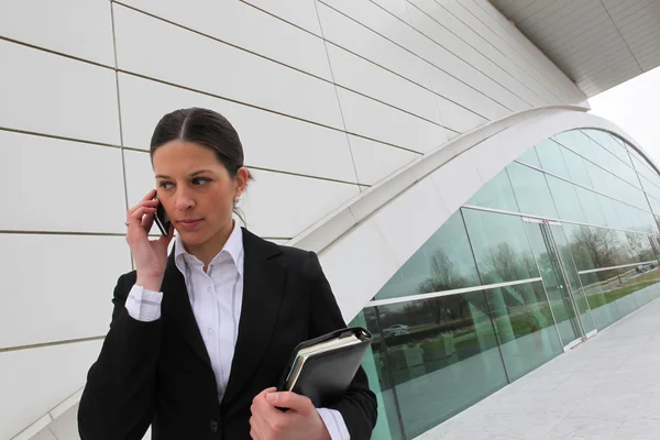 Бізнес-леді на мобільному телефоні поза офісною будівлею — стокове фото