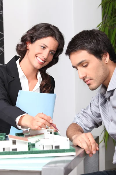 Businesswoman showing a model of a house to a client — Stock Photo, Image