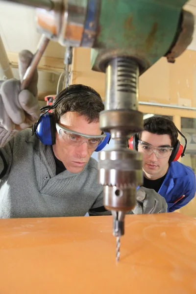 Blue collars using drillhead in workshop — Stockfoto