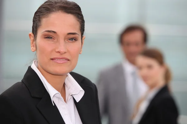 Portrait of a businesswoman with colleagues out of focus in the background — Stok fotoğraf