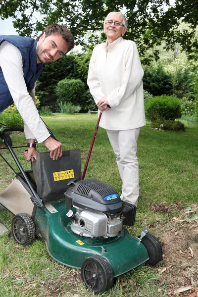 Senior with gardener and lawnmower — Stok fotoğraf