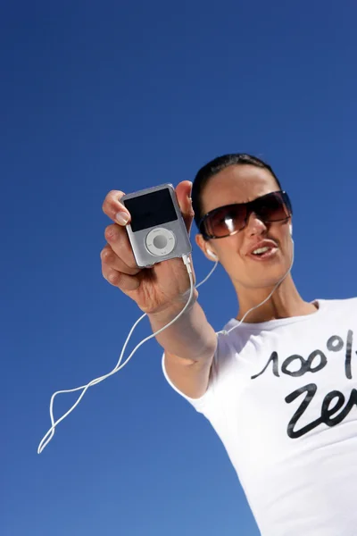 Morena usando óculos de sol ouvindo música através de mp3 player — Fotografia de Stock