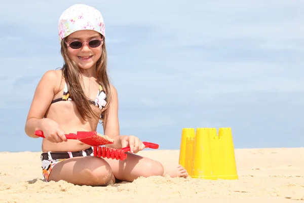 Young girl making sandcastles on a beach — Stok fotoğraf