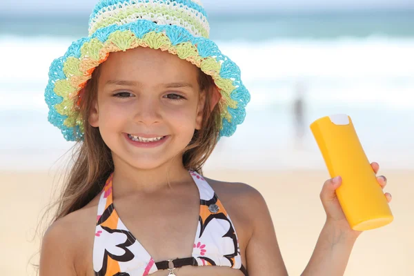 Little girl on the beach with a sun cream — Stock Photo, Image