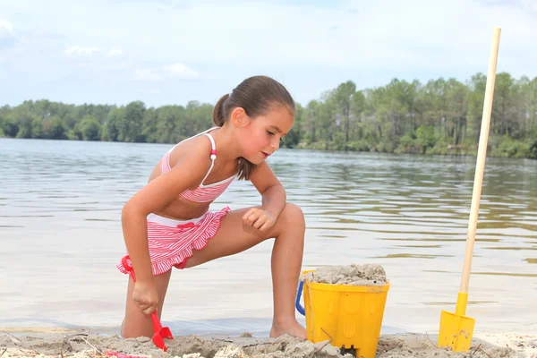 Young girl building sandcastles on the beach — Stok fotoğraf