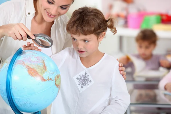 Colegiala enseñando geografía con globo — Foto de Stock