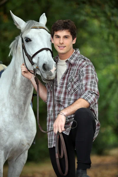 若い男が彼の馬の世話をして — ストック写真
