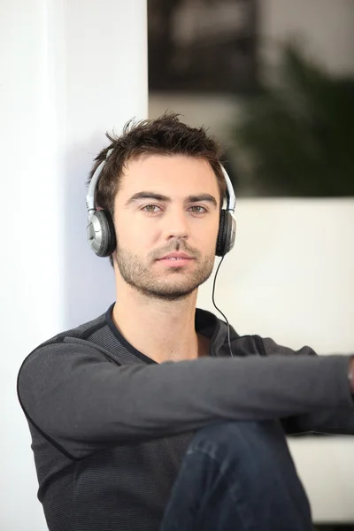Muž poslouchá hudbu přes sluchátka — Stock fotografie