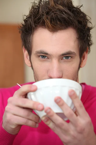 Young man drinking out of a bowl — Stockfoto