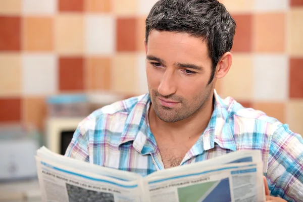 Homem lendo um diário na cozinha — Fotografia de Stock