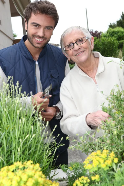 Young man and elderly woman gardening — Stok fotoğraf