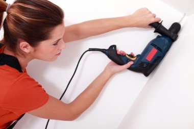 Handywoman drilling a hole in the ceiling clipart