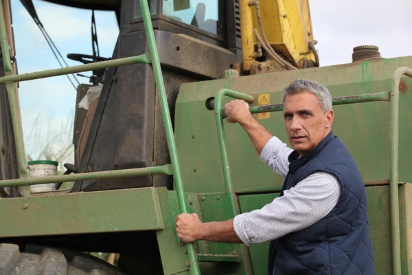 Farmer getting into tractor — Stockfoto