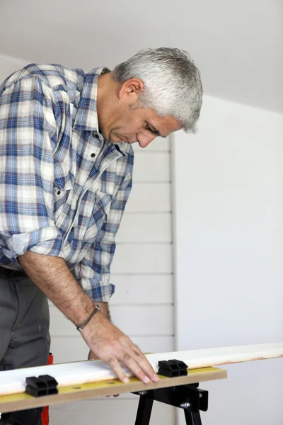 Elderly handyman preparing plank of wood to be cut — Stock Photo, Image