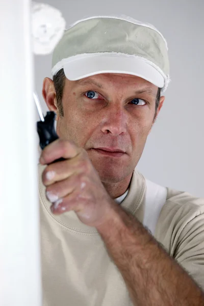 Painter in white using a white roller — Stockfoto