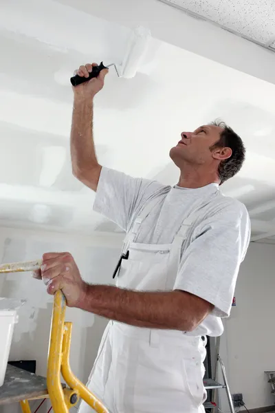 Man painting ceiling with roller — Stockfoto