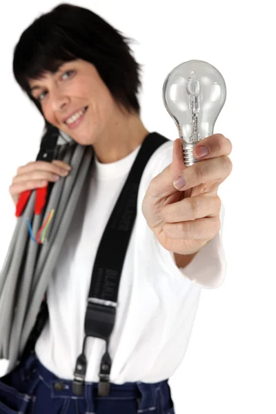 Eletricista feminino mostrando lâmpada — Fotografia de Stock