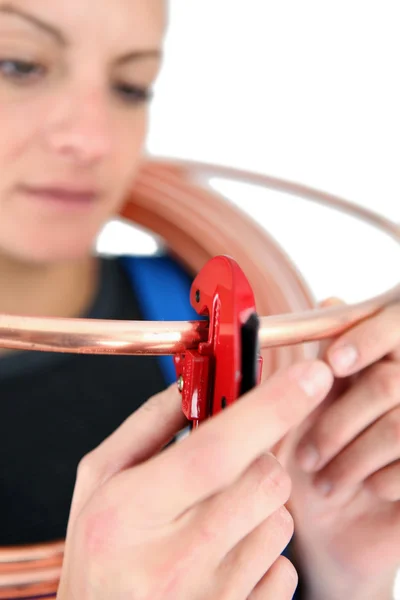 Mulher trancando uma chave de tubo em um anel de cobre — Fotografia de Stock