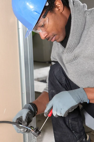 Afro-American laborer installing wiring — Stockfoto