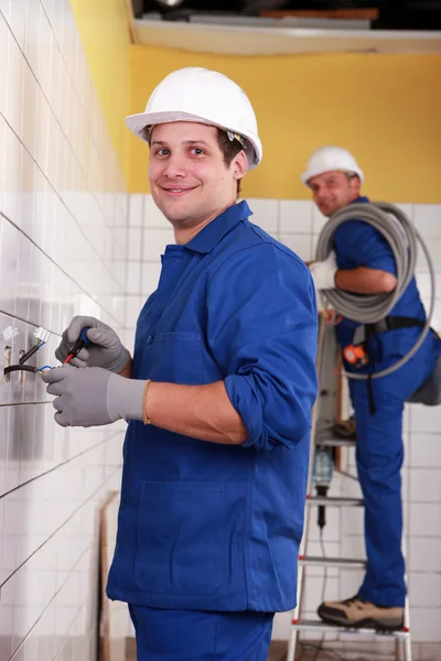 Electricians working in a tiled room — Stok fotoğraf