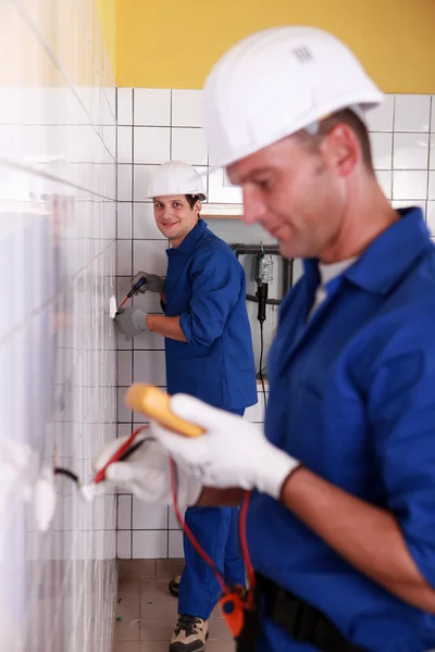 Electricians working in a tiled room — Stock Photo, Image