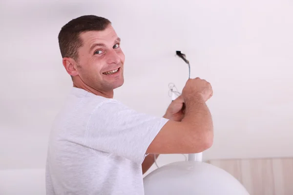 Man at home fixing ceiling light — Stockfoto
