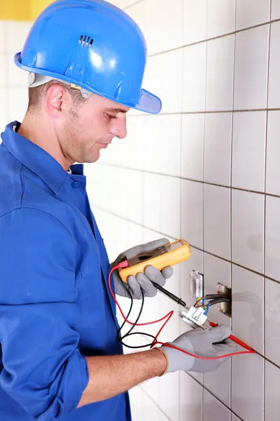 Plumber checking wiring with a voltmeter — Stok fotoğraf