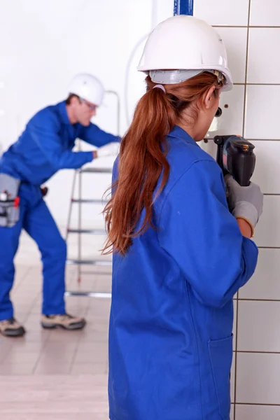 Female electrician drilling a wall — Stockfoto