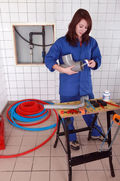Female plumber glueing pipe together — Stok fotoğraf