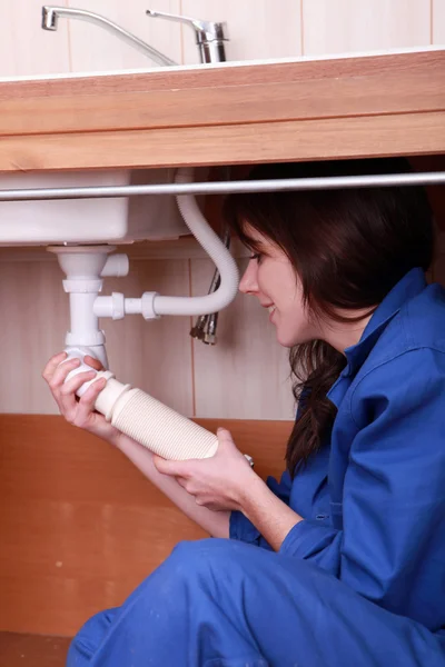 Female plumber fitting a kitchen sink — Stock Photo, Image