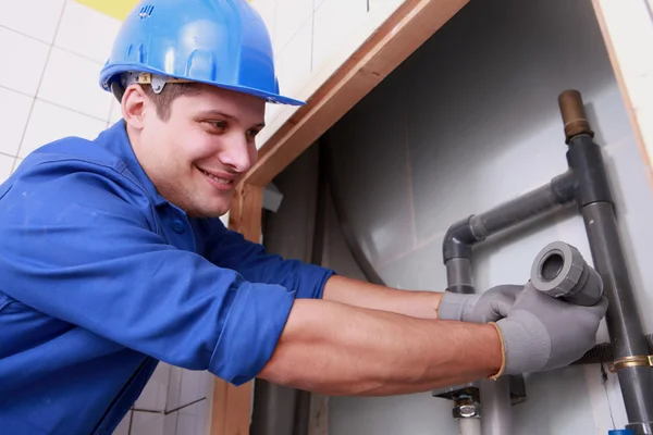Young plumber fitting water pipes — Stockfoto