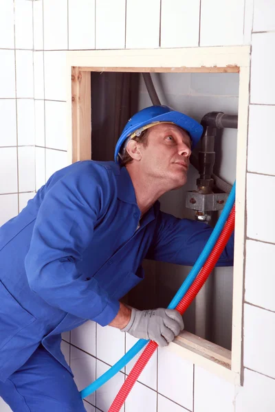 Plombier installant des tuyaux d'eau chaude et froide — Photo