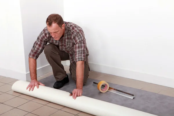 Muž rozvinutí koberec — Stock fotografie