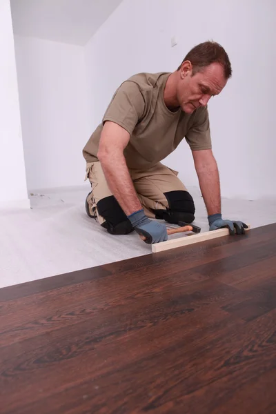 Man tot vaststelling van een houten vloer — Stockfoto