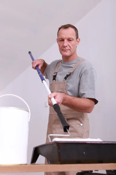 Décorateur trempant son rouleau de plafond dans un plateau de peinture blanche — Photo