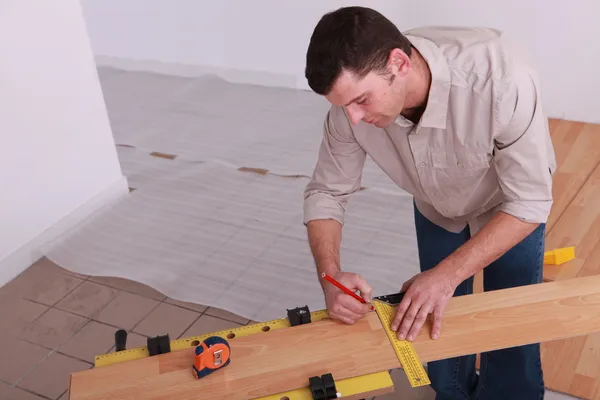 Muž měřící prkno laminátové podlahy — Stock fotografie