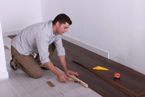 Artesanato colocando um piso de madeira — Fotografia de Stock