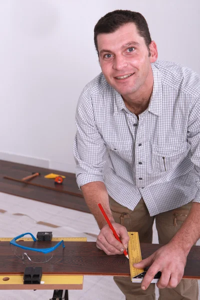 Mann markiert Dielenbrett mit Bleistift — Stockfoto