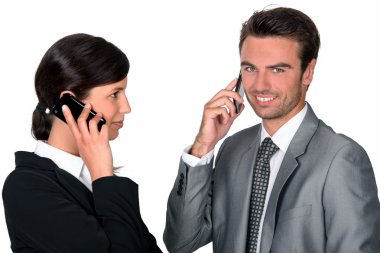 Two businesspeople making simultaneous calls clipart